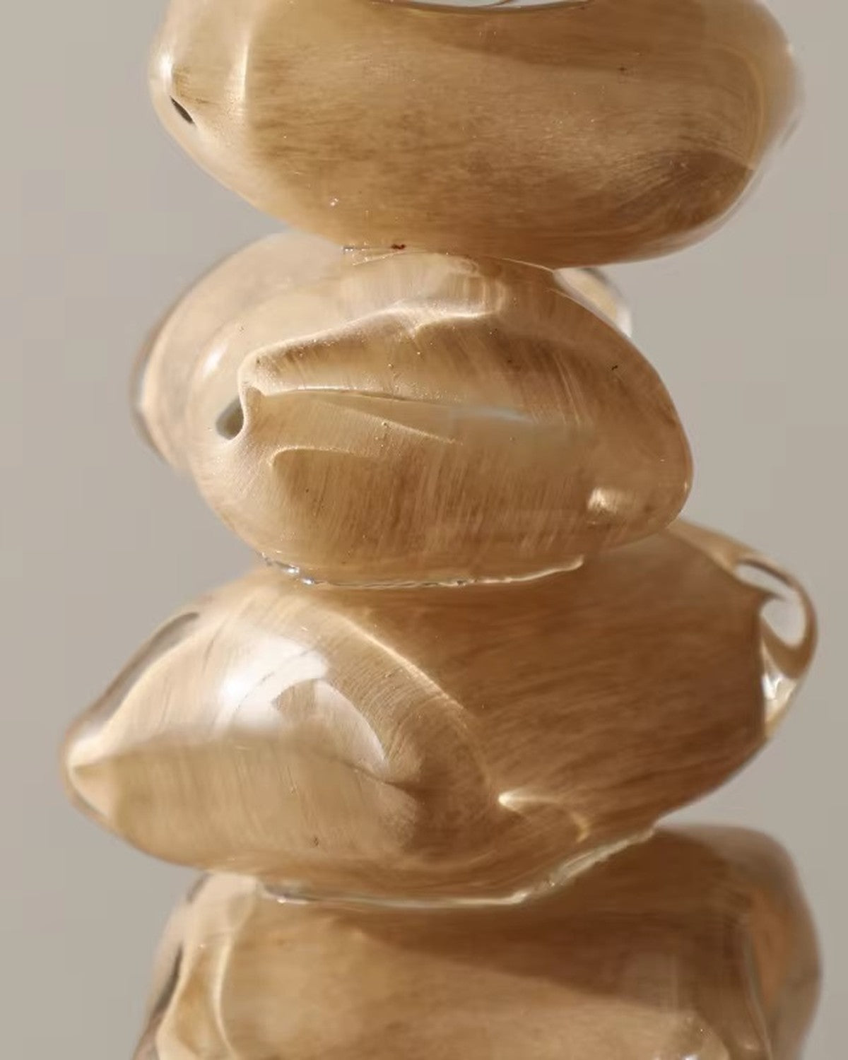 Close-up of stacked, translucent, beige pebble-like forms with internal swirling texture