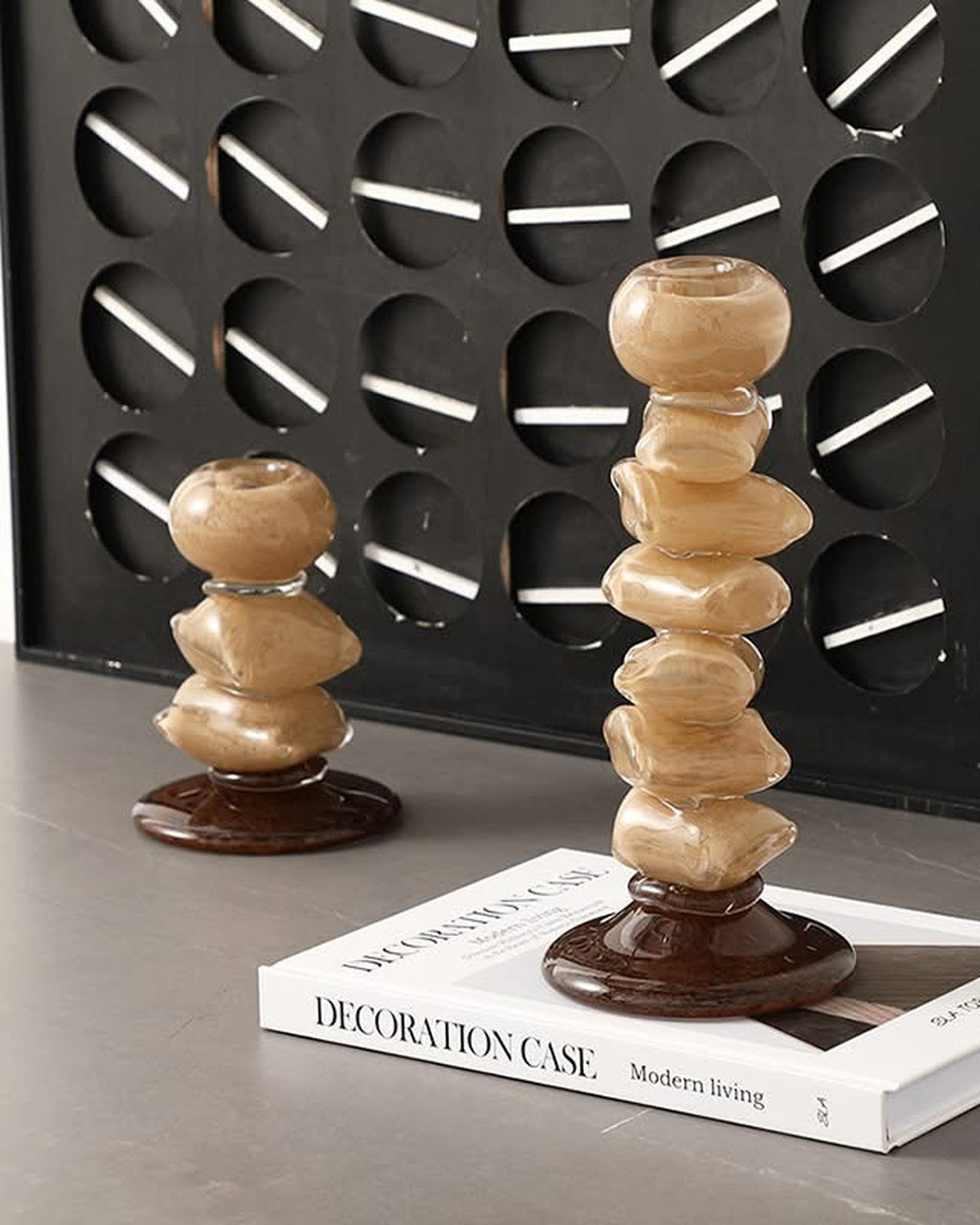 Styled on a console: Two stacked two-tone glass pebble candle holders on a book