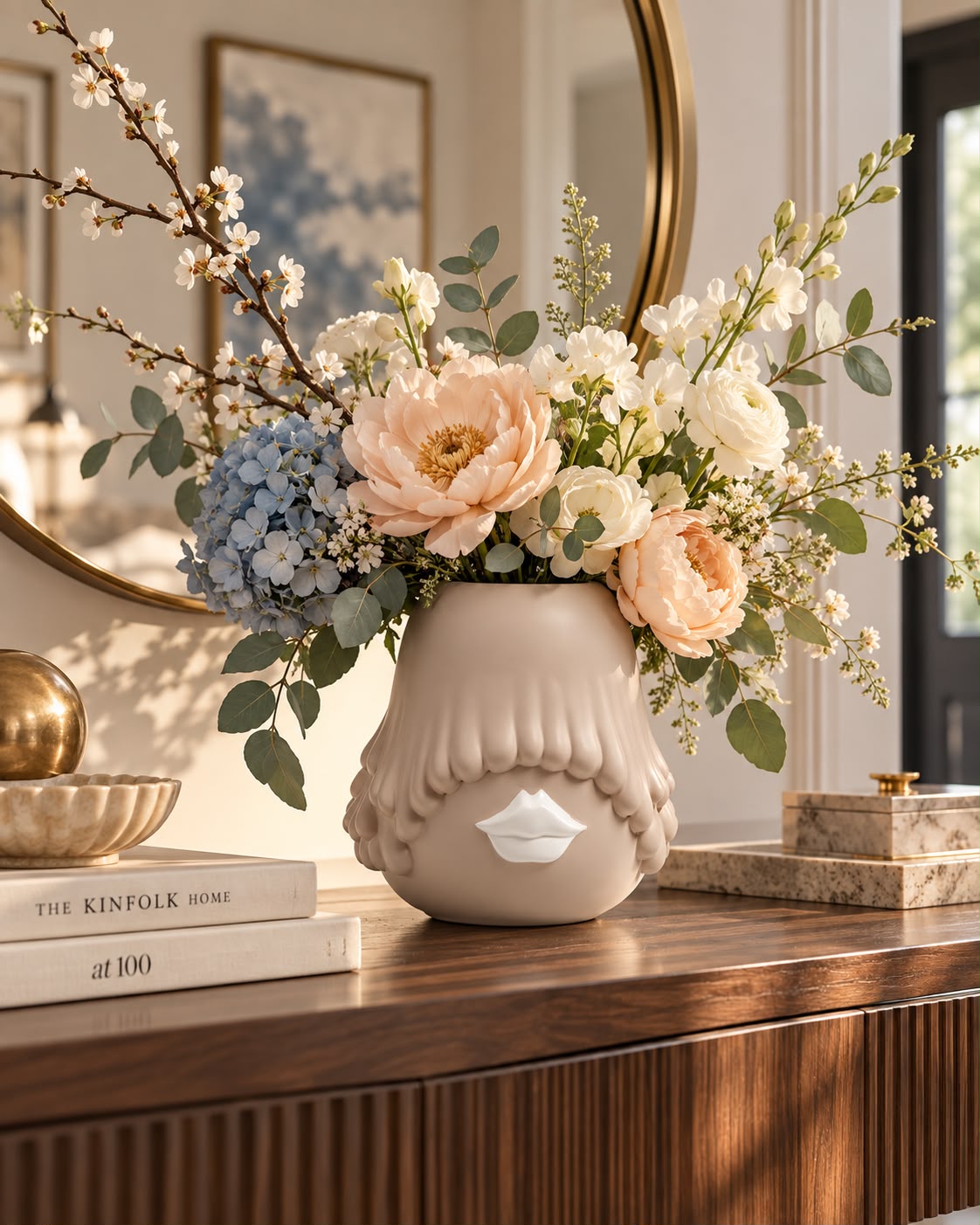 Cream sculptural vase with a lip motif holding spring flowers on a walnut console