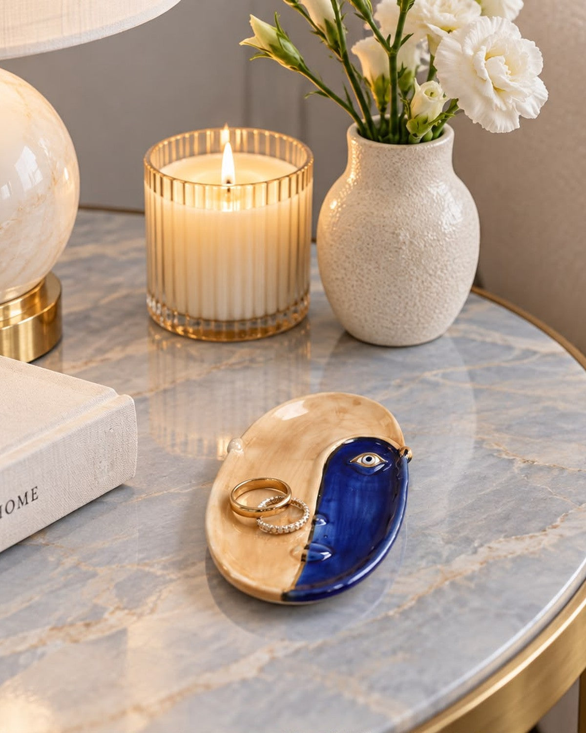 On a marble table: An abstract face plate, split blue and tan, holds two rings