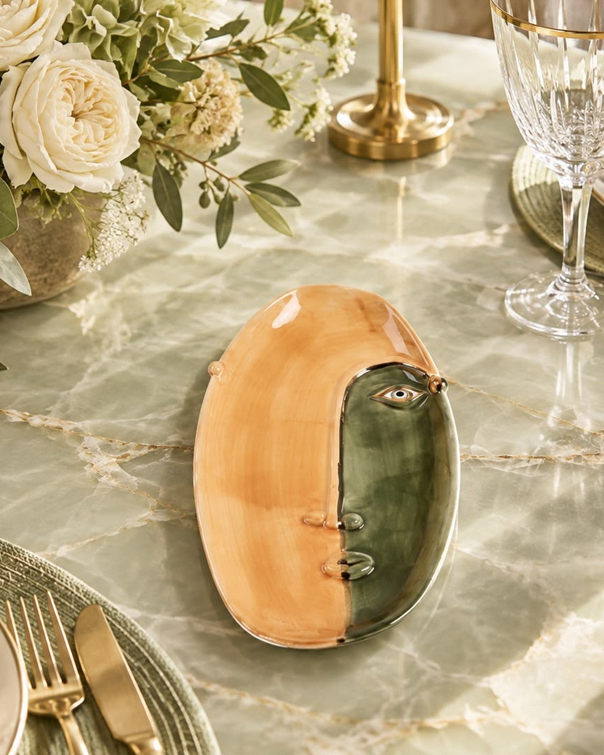 Close-up of an abstract face plate, half tan and half green, on a marbled table