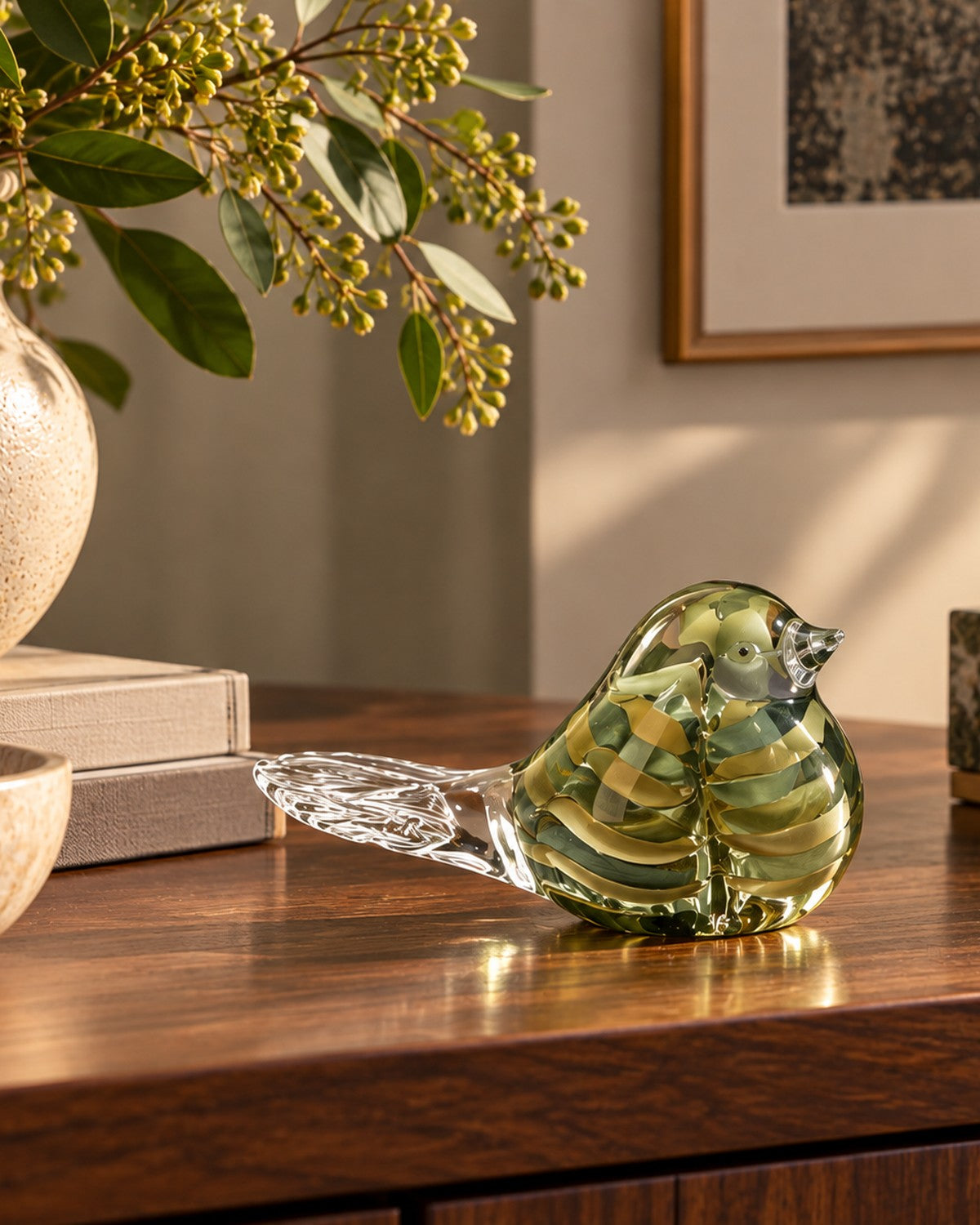 Close-up of a green and clear glass bird ornament on a dark wooden surface