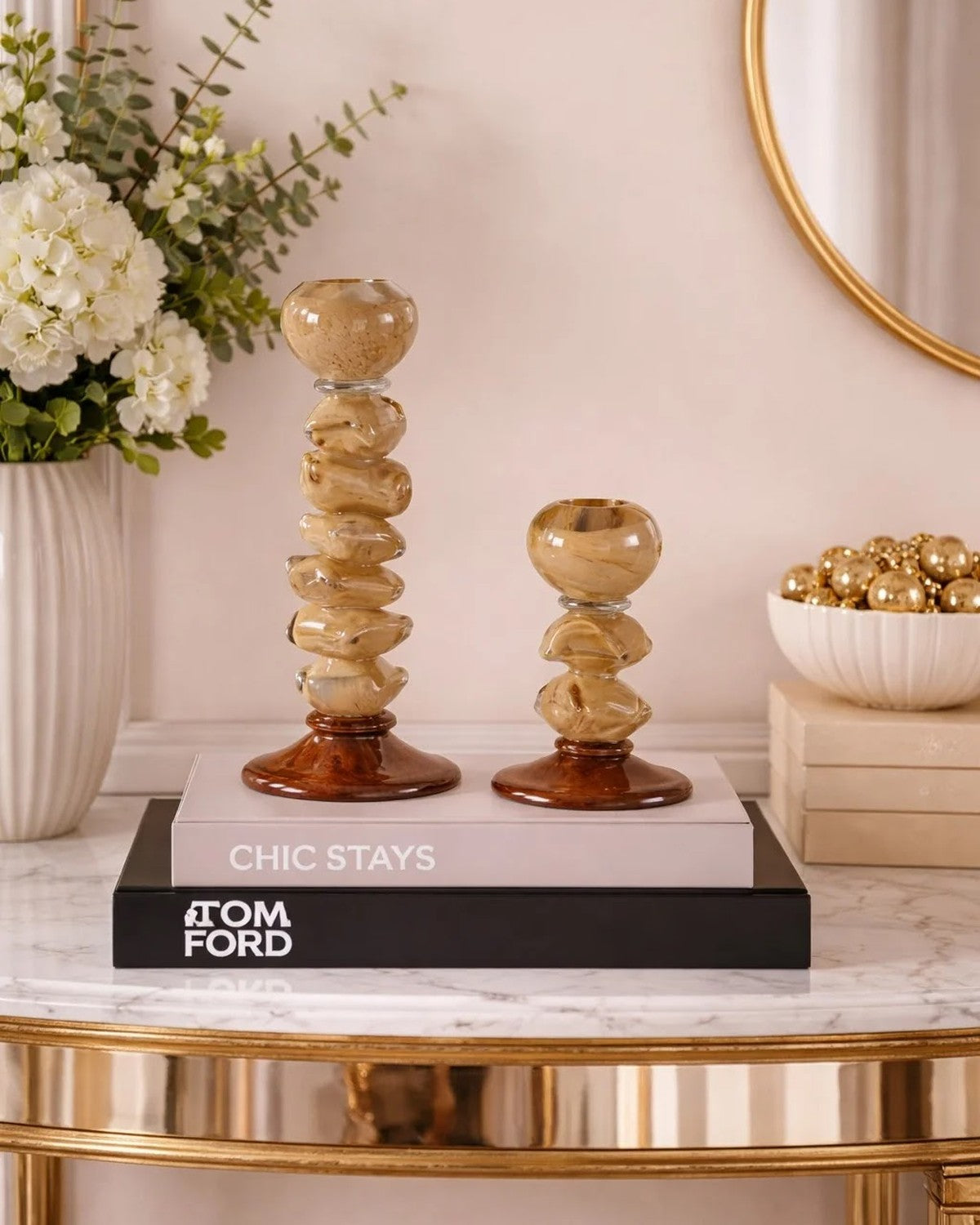 Styled on a console: Two amber-toned pebble candle holders sit on stacked books