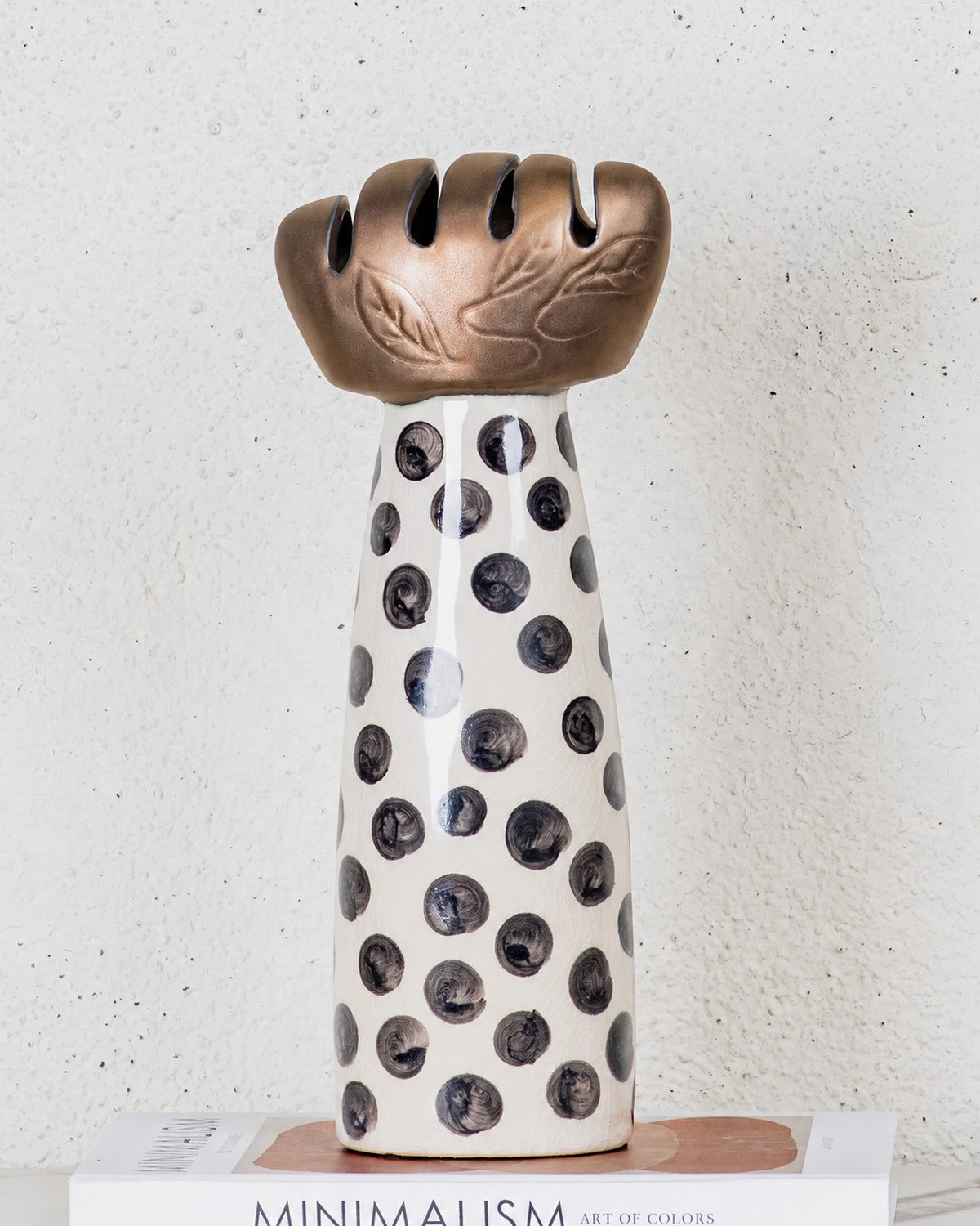 Close-up of a ceramic mushroom sculpture with black polka dots, on a book