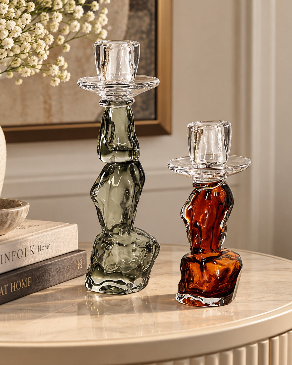 Styled on a console: Two irregular-shaped glass candle holders, one green, one amber