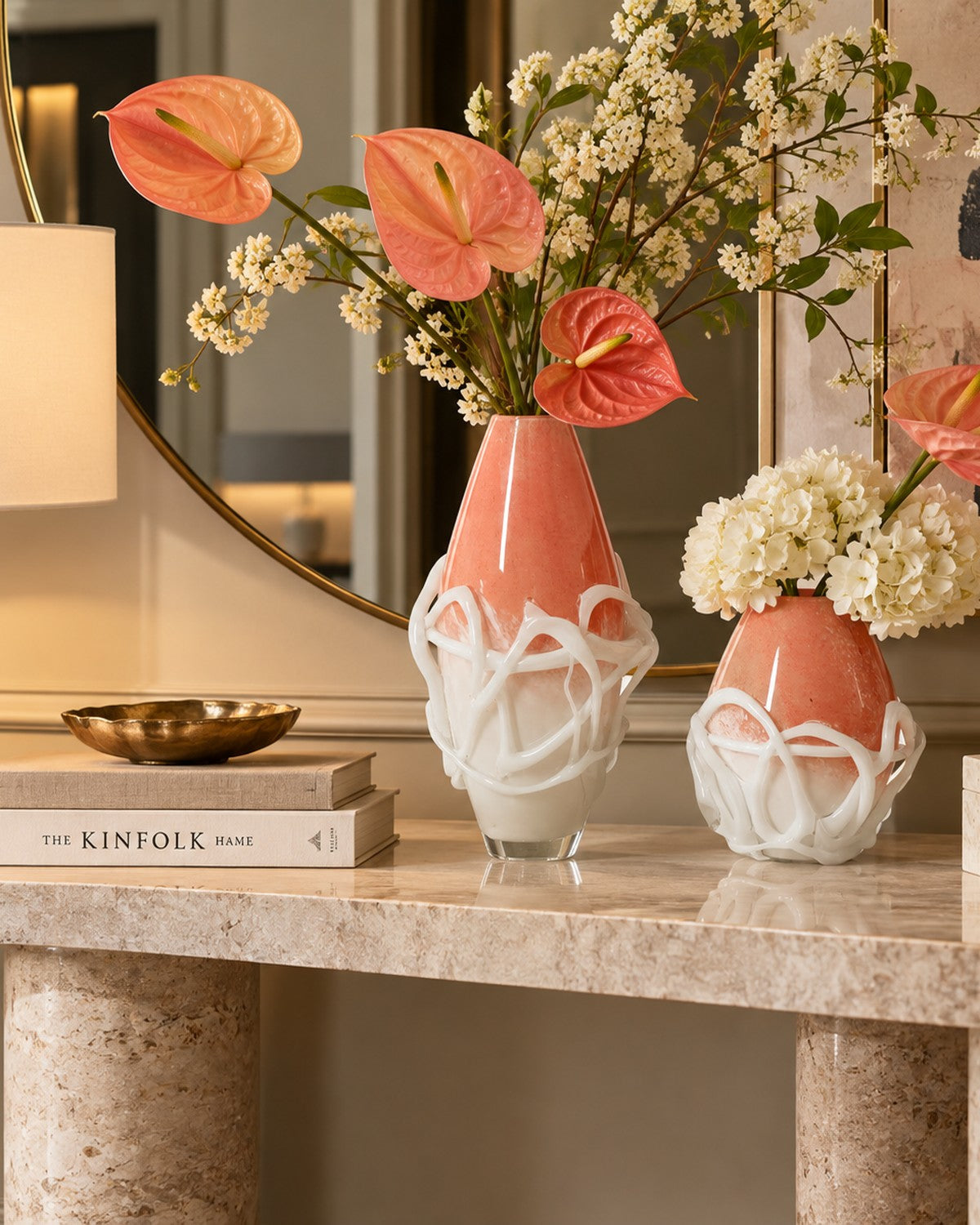 Styled on a console: Two orange and white vases with white swirls, filled with flowers