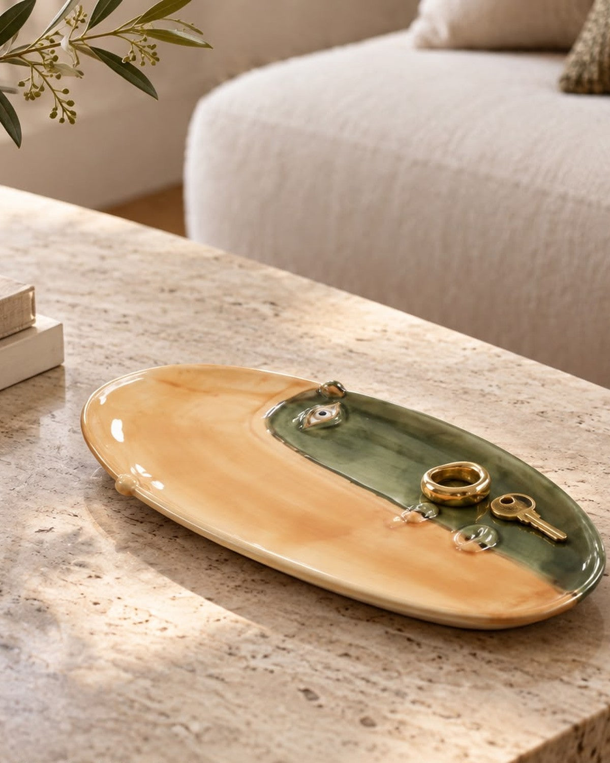 Close-up of an oval, tan and green plate with abstract eyes, holding a ring and key